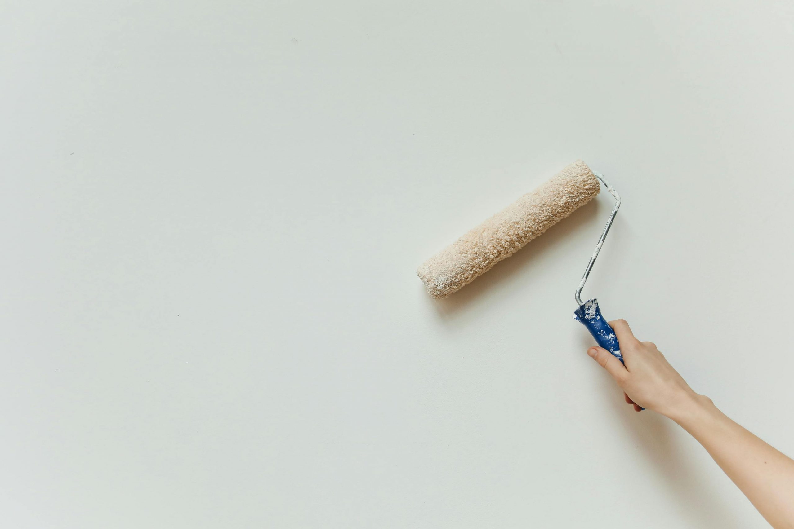 paint roller being used on a white wall