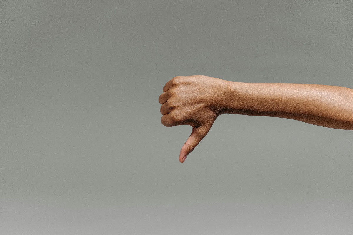thumbs down hand gesture with plan wall in background